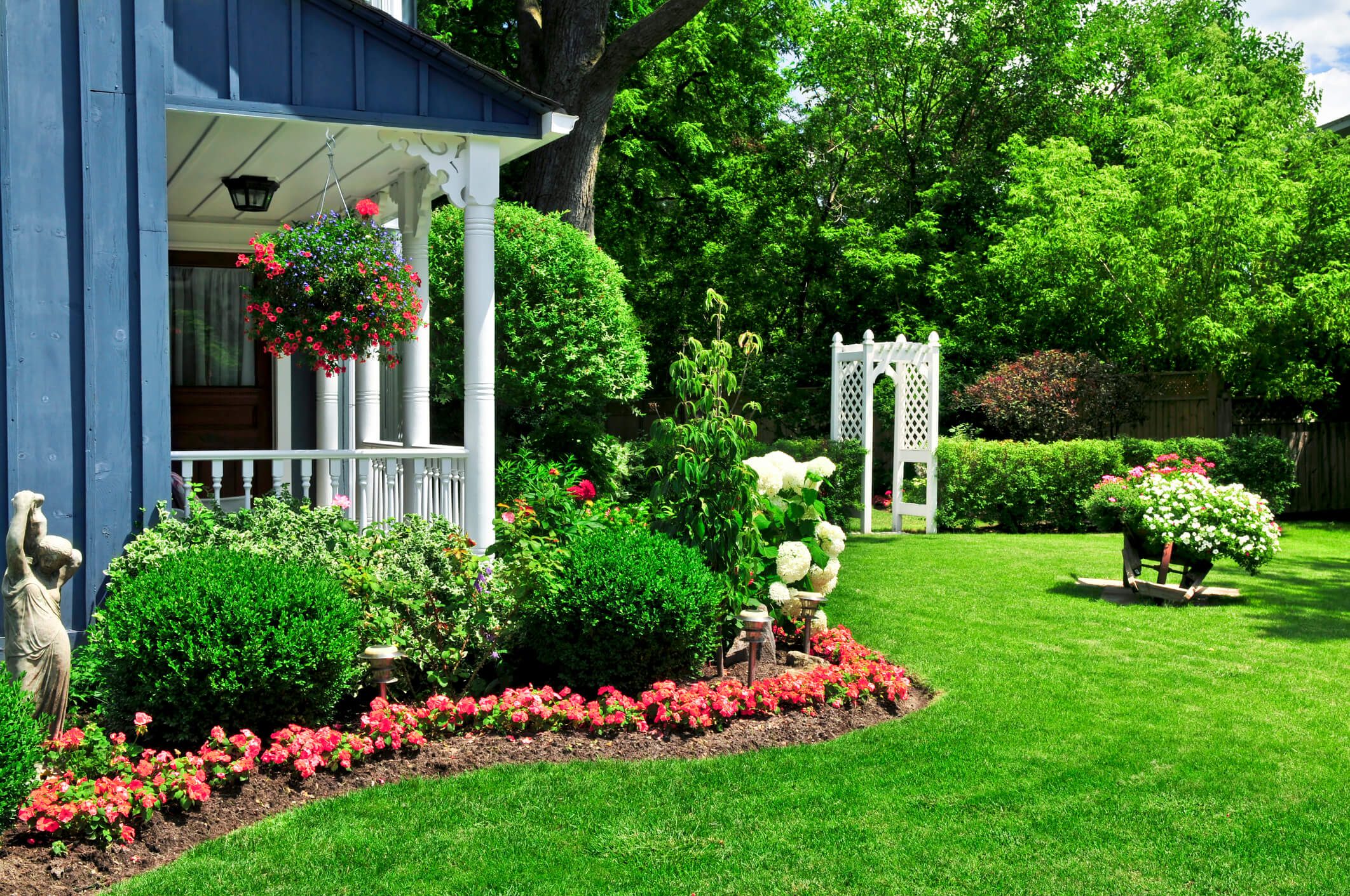 Lush garden with flowers and white arbor.