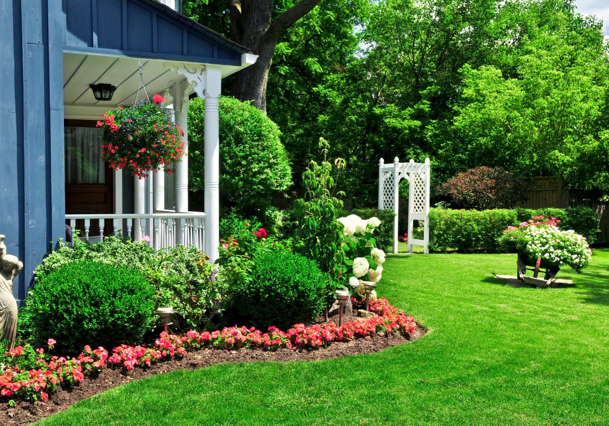 Lush garden with flowers and white arbor.